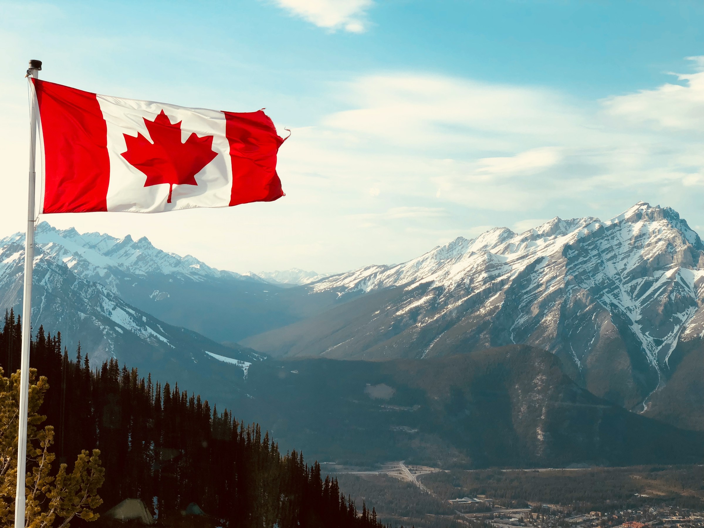 The Canadian flag flying above the Rocky Mountains near Banff, Alberta